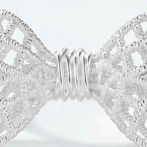 Macro detail of intricate lace-pattern bow in S925 sterling silver with woven texture