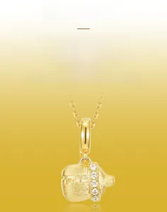 Détail du pendentif biberon montrant la texture dorée brossée main et les zircons blancs