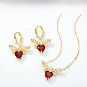 Macro detail of bee earrings with red heart gemstone and zircon wings in gold finish