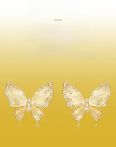 Détail des boucles d'oreilles papillon en or brossé faites à la main avec zircone