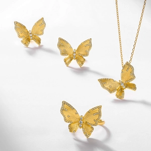 Parure papillon en or brossé comprenant collier, boucles d'oreilles et bague sur fond blanc