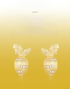 Detailed close-up of handmade brushed gold carrot earrings with inlaid white zircons