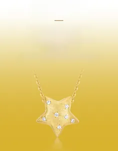Macro shot of gold star necklace pendant with brushed texture and small inset diamonds