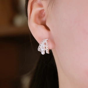 Elegant lace hollow silver earrings with three pearls and diamonds worn by a model