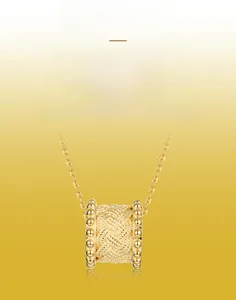 Detailed close-up of a gold-plated cylinder pendant featuring hand-brushed textured metal
