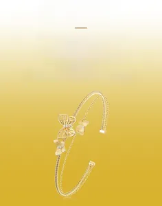 Detail of gold double-layer twisted bangle featuring handcrafted brushed metal butterflies