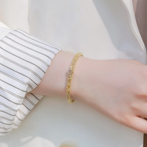Elegant gold hollowed silver bangle with labradorite gemstone worn by model in white suit