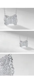 Macro du pendentif nœud argenté avec texture dentelle et zircons étincelants