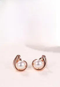Détail des boucles d'oreilles escargot en or rose avec perle blanche et éclats brillants