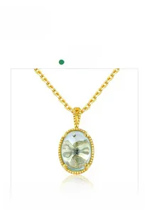 Gros plan d'un pendentif ovale en pierre verte sur une élégante chaîne de collier dorée