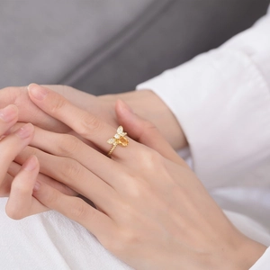 Dettaglio anello ape con gemma gialla e diamanti bianchi sulla mano di modella