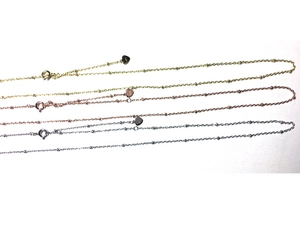 Détail de colliers chaîne satellite en or, or rose et argent avec pendentifs cœur