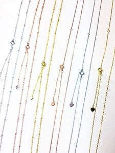 Gros plan de chaînes à billes en argent S925 avec pendentifs cœur en argent, or et rose