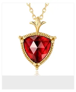 Dettaglio di una collana dorata vintage con ciondolo di granato sfaccettato e bordo a perline