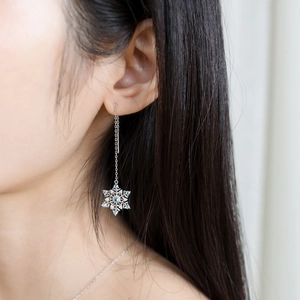 Close-up of S925 silver snowflake drop earrings with blue stones on a female model
