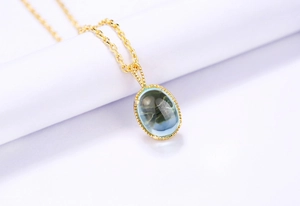 Détail d'un collier doré vintage avec pierre précieuse sarcelle et bords perlés fins