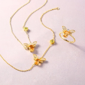 Set gioielli ape in argento con collana pendente in citrino e anello aperto su sfondo viola