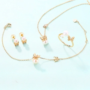 Elegant gold butterfly jewelry set with white freshwater pearls on mint background