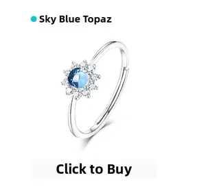 Macro detail of sky blue topaz stone surrounded by small zircons on a silver sunflower ring