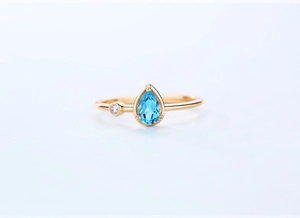 Macro shot of pear-cut Swiss blue topaz and white zircon on a gold-plated S925 silver ring