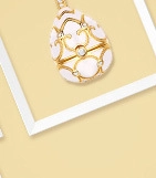 Detalle del colgante de huevo estilo Fabergé con esmalte rosa y patrón dorado sobre fondo amarillo