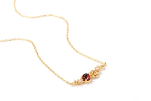 Macro detail van granaat bloemen hanger in 925 zilver verguld met roos motief