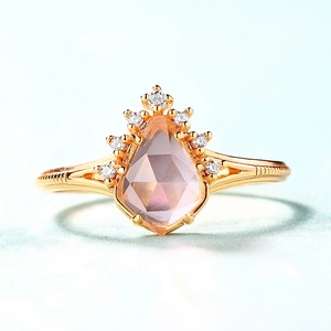 Elegant gold crown ring featuring a pear-cut pink quartz stone with cubic zirconia accents