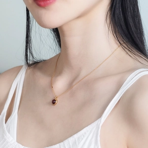 Close-up of a minimalist gold S925 silver necklace with a red garnet pendant on neck