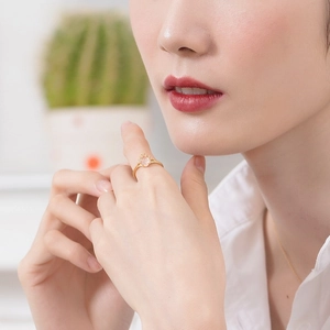 Detail of a pear-cut pink quartz ring in gold with diamond accents worn by a model