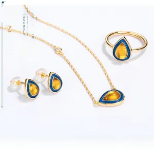 Detailed set of gold-plated amber teardrop necklace, ring, and earrings with blue enamel