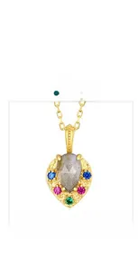 Macro view of gold-plated pendant with pear-shaped grey stone and multi-color gems