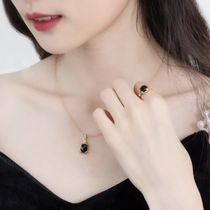 Close-up van vergulde zilveren halsketting en ring set met zwarte onyx hangers bij model