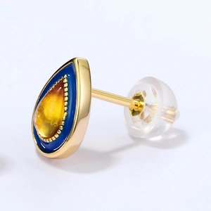 Macro view of S925 teardrop amber earring with blue enamel and gold beaded border