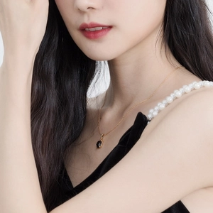 Detailweergave van een elegante gouden ketting met zwarte agaat hanger op een model