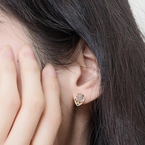 Macro shot of gold-plated leaf earring with natural labradorite on a model's ear