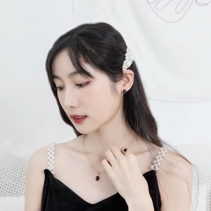 Detail of luxury gold plated silver earrings with black agate on elegant female model