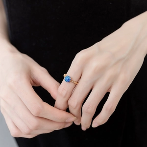 Detailed shot of retro engraved gold ring with sea blue opal stone worn on finger