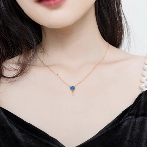 Élégant collier en or avec pendentif opale bleue porté par un mannequin en robe noire