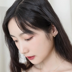 Close-up of heart-shaped gold stud earring with dark labradorite inlay on female model