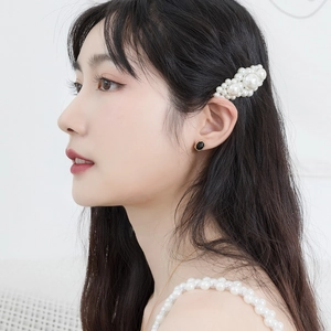 Close-up of elegant gold-plated silver earrings with black round studs and pearl hair clip