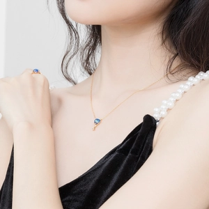 Détail d'un ensemble de bijoux en opale bleue avec chaîne dorée et bague sur mannequin