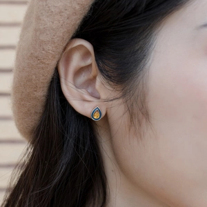 Detailed close-up of water drop stud earring with amber stone and blue enamel on ear