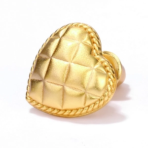 Detailed close-up of heart-shaped gold earring with quilted pattern and rope border