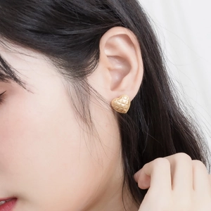 Close-up of vintage heart-shaped gold studs with quilted texture on model's ear