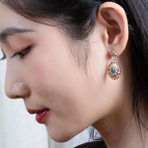 Detail view of vintage gold sunflower earrings with green agate and zircon on female model