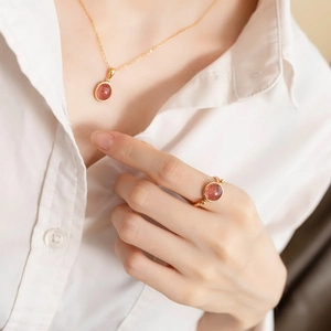 Dettaglio del set di gioielli in cristallo fragola con collana e anello su camicia bianca
