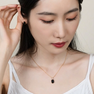 Primo piano di elegante set collana dorata e orecchini in onice nera su modella