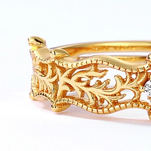Macro detail of vintage gold-plated vine pattern ring with intricate filigree and zircon