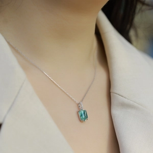 Dettaglio di modella con ciondolo verde taglio smeraldo e catena in argento lucido