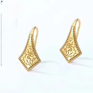 Macro detail of geometric gold earrings with intricate floral relief and vintage finish